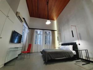 1 dormitorio con 1 cama, TV y silla en The Pitoulis Mansion, en Igoumenitsa