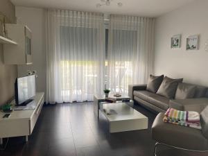 a living room with a couch and a tv at Golfhotel Hebelhof (Wellness-Appartement) in Welmlingen