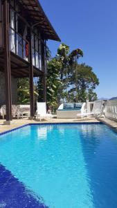 una gran piscina azul con sillas y un edificio en Recanto J&R en Angra dos Reis