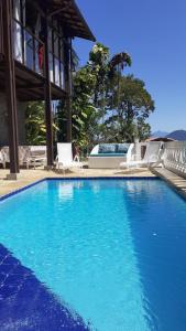 a large blue swimming pool with chairs and a building at Recanto J&R in Angra dos Reis