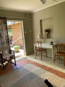 ein Wohnzimmer mit einem Tisch, Stühlen und einem Schreibtisch in der Unterkunft 1 bed garden flat in Umzumbe