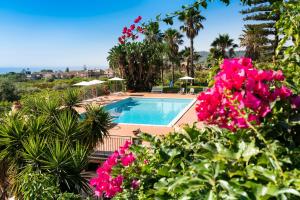 een resort met een zwembad en roze bloemen bij Suasor in Acireale