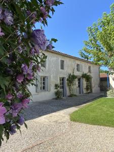 - une vue sur l'extérieur d'une maison blanche ornée de fleurs violettes dans l'établissement Gîte des oiseaux, à Préchac