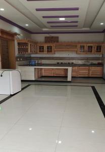 a large kitchen with a white tile floor and a refrigerator at Zujaja Guest House in Bhurban