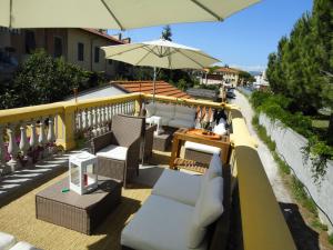 eine Terrasse mit Stühlen und einem Sonnenschirm auf dem Balkon in der Unterkunft Hostel Pisa Tower in Pisa
