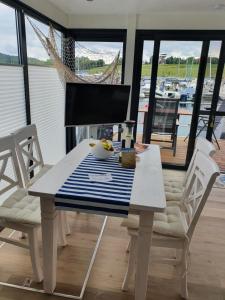 uma mesa e cadeiras brancas com vista para um barco em Hausboot Casa di Lago em Braunsbedra