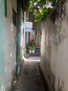 Une allée avec un panneau sur le côté d'un bâtiment dans l'établissement Losmen Fadel Malioboro Jogja, à Yogyakarta