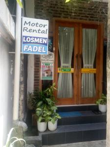 un panneau devant une porte avec des plantes en pot dans l'établissement Losmen Fadel Malioboro Jogja, à Yogyakarta