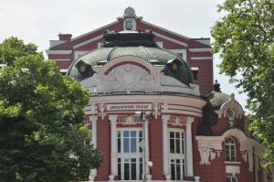 un edificio rojo con un reloj encima en Arlequin Apartment, en Varna