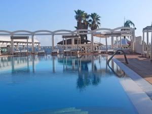 una piscina con agua azul, sillas y árboles en Hotel Residence La Corvetta en Monopoli