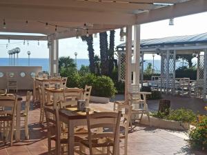 eine Terrasse mit Tischen und Stühlen mit Meerblick im Hintergrund in der Unterkunft Hotel Residence La Corvetta in Monopoli