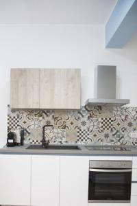 a kitchen with white cabinets and a stove top oven at Appartamento il Mulino in Orbetello