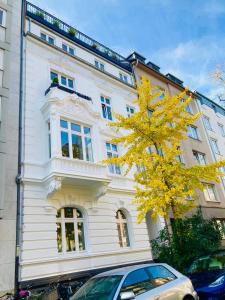 ein weißes Gebäude mit einem gelben Baum davor in der Unterkunft Apartment in Pempelfort - Central in Düsseldorf