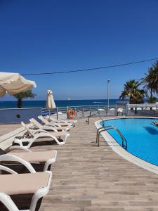 a swimming pool with chairs and the ocean in the background at Eleni Beach Apartment in Stalida