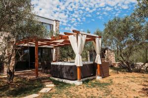 een pergola met een bed in een tuin bij Capesanta atraktivna kamena kučica in Lukoran