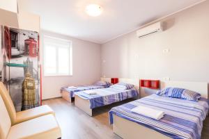 a room with three beds and a chair at Hostel Sunset in Zadar