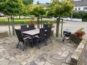a patio with a table and chairs and a grill at Am Osterberg in Büdesheim