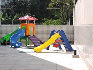 une aire de jeux avec un toboggan et une structure de jeu dans l'établissement Floresta - Enseada Guarujá, à Guarujá