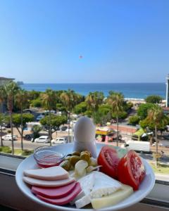 um prato de queijo e fruta com vista para o oceano em Miray Hotel Kleopatra em Alanya