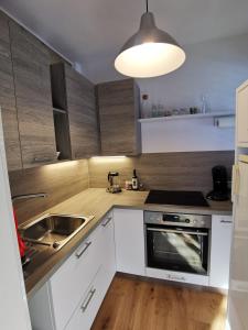 Citycenter Apartment Stadthalle في غراتس: مطبخ بدولاب بيضاء ومغسلة وموقد