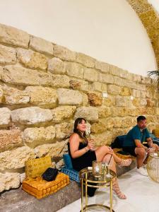 um grupo de pessoas sentadas ao lado de uma parede de pedra em Palazzo del Poeta - Dimora Contemporanea em Palermo
