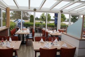 a restaurant with tables and chairs and windows at Hotel & Restaurant Am Wasser in Breege