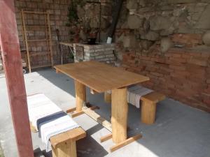 CserháthalápにあるNagyhalápのレンガの壁の前に木製のピクニックテーブルとベンチ