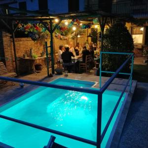 Cà Nostra B&B Home Restaurant في Portacomaro: وجود مسبح في الليل مع وجود اشخاص يجلسون في المطعم
