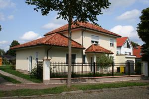 una casa blanca con una valla negra en Business Lounge Potsdam en Potsdam