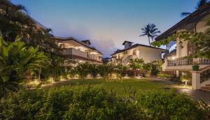 a courtyard of a resort with a lawn and buildings at Heritage Village Resort & Spa Goa in Cansaulim