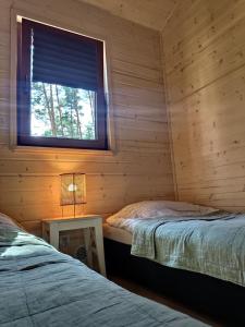 a log cabin with two beds and a window at Zakątek Wdzydze z widokiem na jezioro -domek nr 19 in Borsk