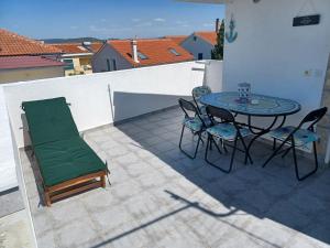 a patio with a table and chairs on a roof at Apartmani Jakovljevic in Murter