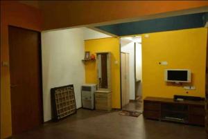 sala de estar con paredes amarillas y blancas y TV en Shattarka Villa en Alibaug