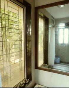 baño con espejo grande y ventana en Shattarka Villa en Alibaug