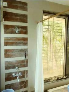 baño con cortina de ducha y ventana en Shattarka Villa en Alibaug