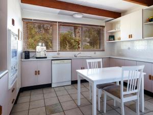 a white kitchen with a white table and chairs at Bennett's Beach Cottage in Hawks Nest