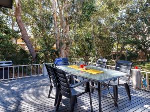 a table and chairs on a deck with trees at Bennett's Beach Cottage in Hawks Nest