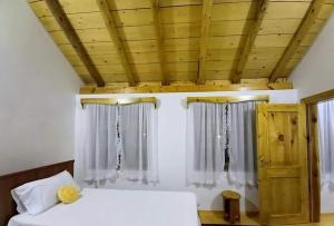 a bedroom with two beds and a wooden ceiling at Bujtina Peshtan Guesthouse&Camping in Tepelenë