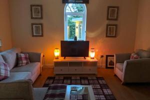 a living room with a couch and a laptop on a table at Tarff Church Sunday school. With hot tub and sauna in Twynholm