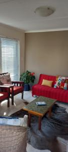 a living room with a red couch and a table at Sea Cottage in Mossel Bay