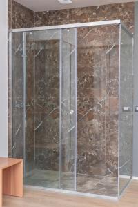 a glass shower in a room with a stone wall at Ventus Hotel in Ksamil