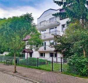 un edificio bianco con una recinzione di fronte di Dom Gościnny Amare a Pobierowo