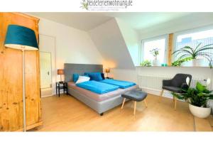 1 dormitorio con 1 cama azul y 1 silla en heideferienwohnung - die neue Ferienwohnung en Walsrode