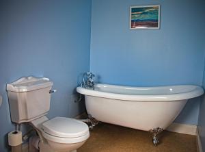 a bathroom with a white tub and a toilet at Arthur's Cottage in Dumfries +44 photos