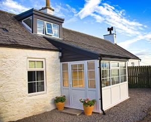 a garage with doors and windows on a house at Arthur's Cottage in Dumfries
