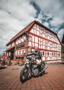 a man sitting on a motorcycle in front of a building at Landgasthof Zum Stern Wasserkuppe Rhön in Poppenhausen