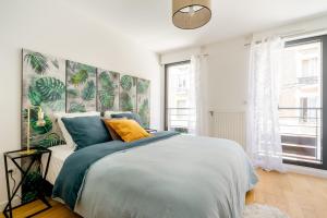 ein Schlafzimmer mit einem großen Bett mit blauen und gelben Kissen in der Unterkunft 3 p 60 M2 Lesapparts Paris-Clichy terrasse équipée et wifi gratuit in Clichy