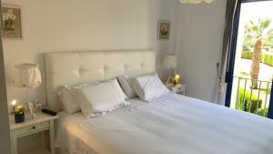 a bedroom with a large white bed with a window at Cabo Roig - Blue Luxury Apartment in Cabo Roig