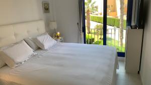 Cabo Roig - Blue Luxury Apartment في كابو رويج: سرير أبيض في غرفة نوم مع شرفة