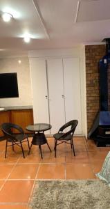 Habitación con 2 sillas, mesa y TV. en Made Guest House, en Sandton